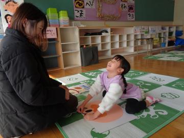 室内で幼児が福笑いをしている様子