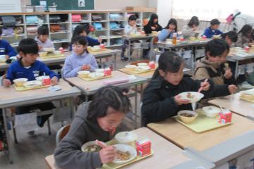 2年生が教室の各自の席に座って給食を食べている様子