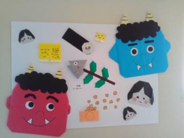 廊下に掲示されている掲示物のようす。赤鬼、青鬼、恵方巻、豆まき、などの折り紙が貼りつけられている。