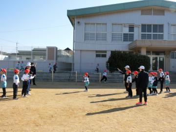 高学年の児童に、長縄に入るタイミングを教えてもらう低学年の児童