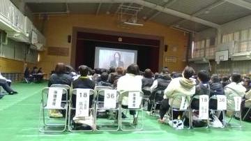 体育館で動画を見る児童と保護者