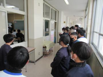 廊下から中学校の授業の様子を見学している小学生たちの様子