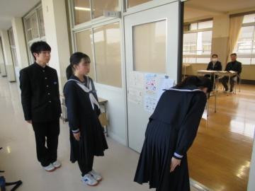 面接練習です。教室の開いたドアの前で、入室前のお辞儀をしている生徒と後ろに並ぶ生徒たちの様子