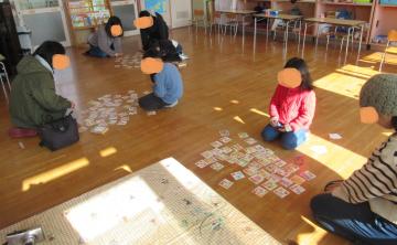 室内でお家の人と一緒にかるたで遊ぶ子ども達の様子