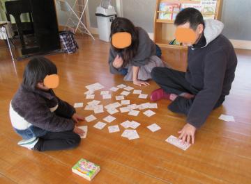 室内で絵札の裏を使ってお家の人と遊ぶ子どもたちの様子