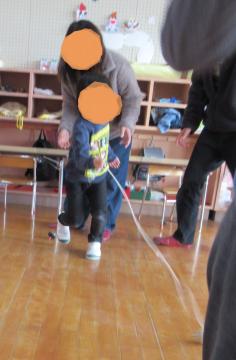 室内でお家の人と一緒にこまを回す子どもの様子