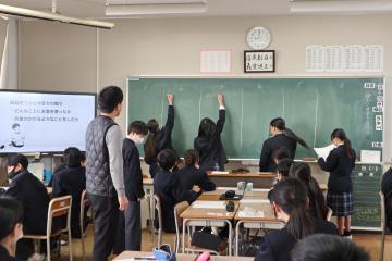 教室で班で出た意見を黒板に書き写す生徒たちの様子