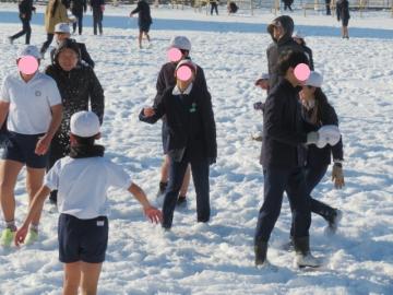 完全防備をして雪遊びをする職員と薄着の子どもたち