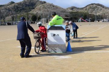 運動場で自転車に乗って練習をする児童