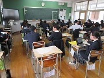 教室の自席に座って近くの生徒と話したながら班別行動の計画をする生徒達1