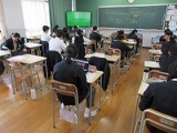 教室の自席に座って近くの生徒と話したながら班別行動の計画をする生徒達2