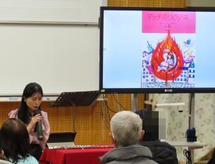 「マッチ売りの少女」をモニターに映し出しながら読み聞かせとピアノ演奏をする女性