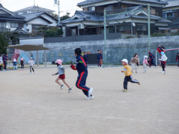 園庭で中学校のお姉さんと鬼ごっこをしている園児たちの様子