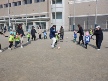園庭で親子でサッカーをしている園児たちの様子