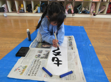 室内で園児が書き初めをしている様子