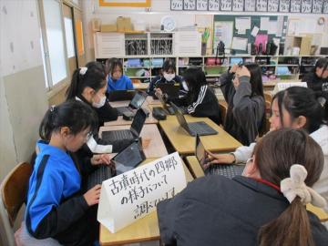 教室の班グループ席に座ってパソコンを開き、班で調べたことを意見交流しているところ