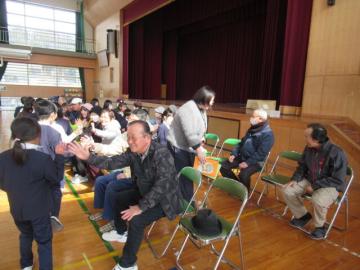 体育館で、ハイタッチでお別れする長寿会の皆さんと1年生の児童たちの様子