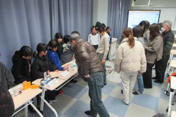 教室内で、児童が保護者に防災グッズを説明している様子