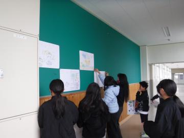 廊下の掲示板にアートクラブの作品を掲示する児童たちの様子