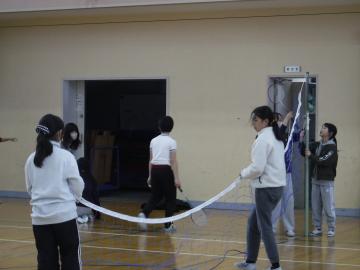 体育館で6年生がバドミントンのネットを片付けるようす
