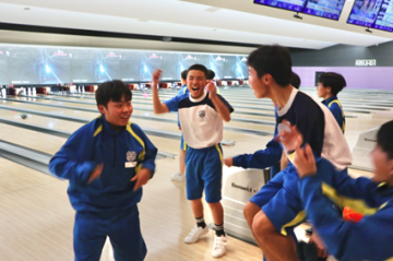 ボウリング場でスペアをとって喜び合う生徒の様子