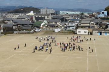 運動場で3年生と6年生がドッヂボールをしている様子