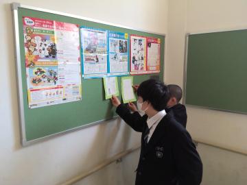 広報福祉部の生徒が掲示物を掲示板に貼っているようす