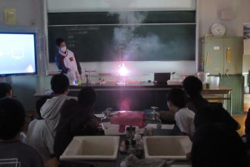 教室内を暗くし、教師の演示実験に見入っている6年生の児童たちの様子