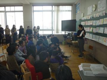 教室内で2年児童たちが先生の説明を聞いている様子