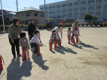 園庭で消火器を使って消火訓練をする園児たちの様子
