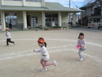 園庭で「鬼は外」と言いながら豆を投げている園児たちの様子