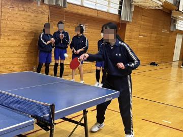 女子生徒が卓球のサーブを打っています。