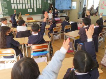 教室で国語の発表会をする子供と、手を挙げるこどもたちのようす