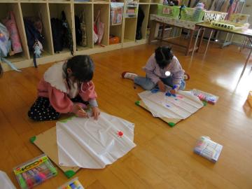 室内で座り、凧に絵を描いている園児たちの様子