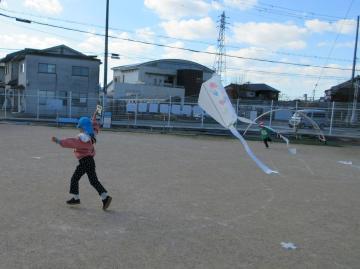 園児が園庭で凧を揚げている様子