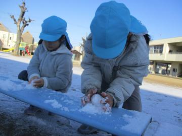 ベンチに積もった雪を集める子供