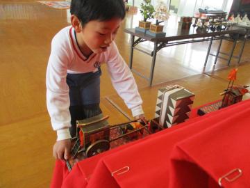 ひな人形の飾りをそっと置いて飾る子供