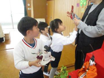 写真を見ながら人形や道具を置いてひな人形を飾る子供たち