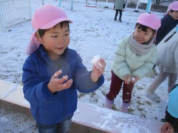 雪を丸めて手に取る子供