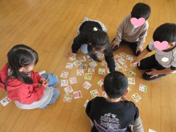 室内の床でカルタ取りをする園児たちの様子