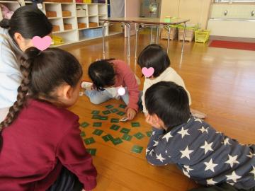 室内の床でメモリーカードをめくっている園児たちの様子