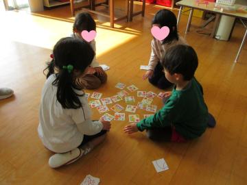 室内の床でカルタ取りをしている園児たちの様子