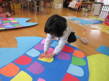 室内の魚の工作に鱗を貼っている園児たちの様子
