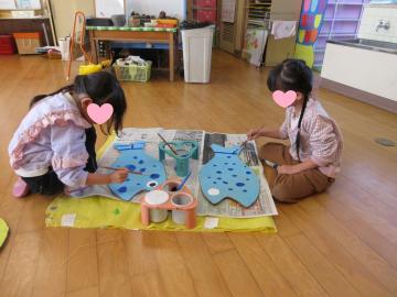 室内の小さい魚の工作に色を塗っている園児たちの様子