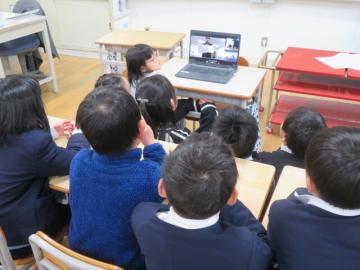 教室でオンラインの絵本読み聞かせをパソコンの前に座って見る児童たちの様子