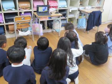 教室でオンラインの絵本読み聞かせをパソコンの前に座って見る児童たちの別の様子