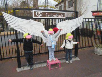 園内でフォトスポットの羽の前で写真撮影をしてもらう園児たちの様子