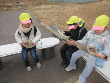 園内のベンチに座り、地図を真剣に見る園児たちの様子