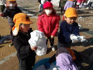 雪の塊を見付けて手に持っている幼児