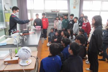 理科実験室で教師の演示実験に注目している6年生の様子